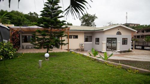 a small house with a tree in the yard at Veke Executive Lodge & Event Center in Cape Coast