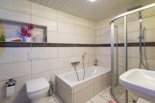 a bathroom with a tub and a toilet and a sink at Ferienhaus Am Steinbach in Ruhpolding