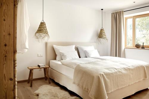 a white bedroom with a white bed and a window at Der Schmiedhof in Bayrischzell