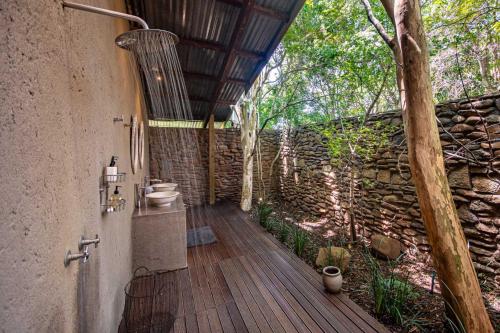 a bathroom with a toilet and a stone wall at Summerfields Rose Retreat and Spa in Hazyview
