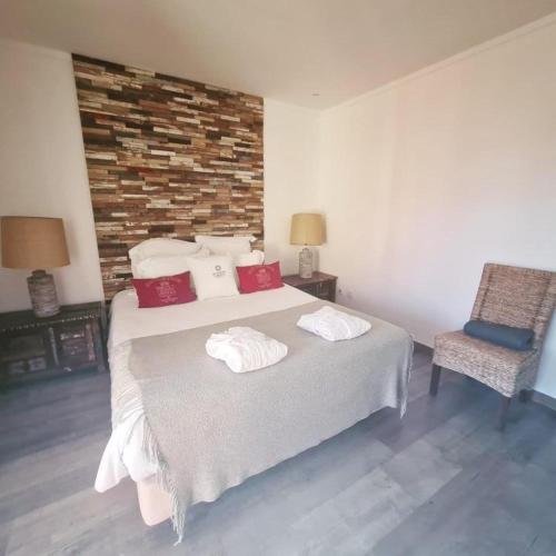 a bedroom with a large bed and a chair at Monte do Cardal in Odeceixe