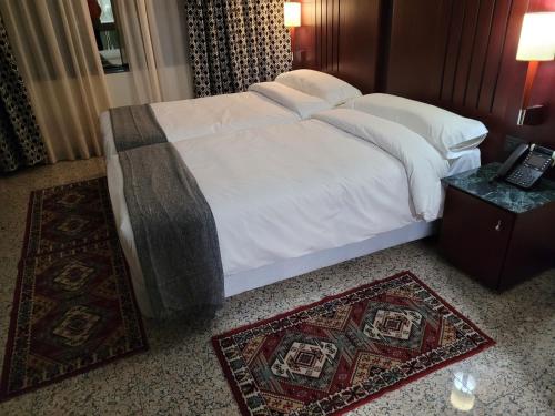 a bed in a hotel room with two rugs at Hotel Amaltea by Executive Sport in Lorca