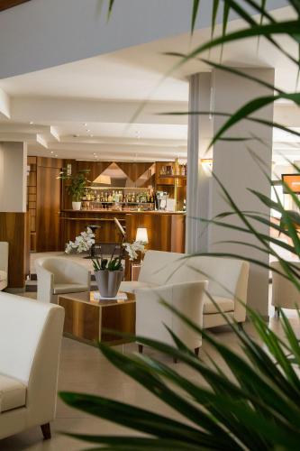 a lobby with white chairs and a bar at Hotel Du Parc in Sirmione