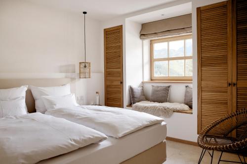 a bedroom with a bed and a chair and a window at Der Schmiedhof in Bayrischzell