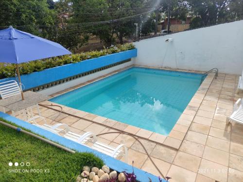 a pool with chairs and an umbrella on a patio at Casa de condomínio para 6 pessoas, tudo a pé, perto do centro e piscinas naturais in Porto De Galinhas