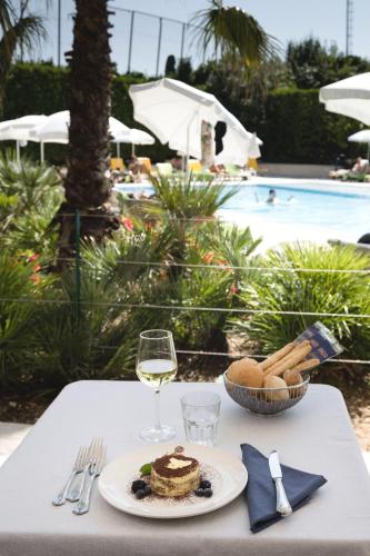 a table with a plate of food and a glass of wine at Hotel Du Parc in Sirmione