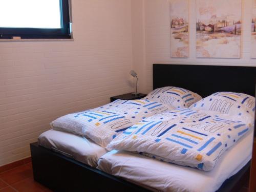 a bed with blue and white blankets and pillows at Bungalow 451 in Tossens in Butjadingen OT Tossens