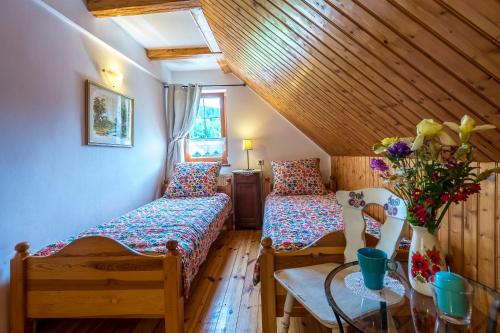 Zimmer mit 2 Betten und einem Tisch mit einer Blumenvase in der Unterkunft Apartamenty Leśniczówka Salamandra in Świeradów-Zdrój