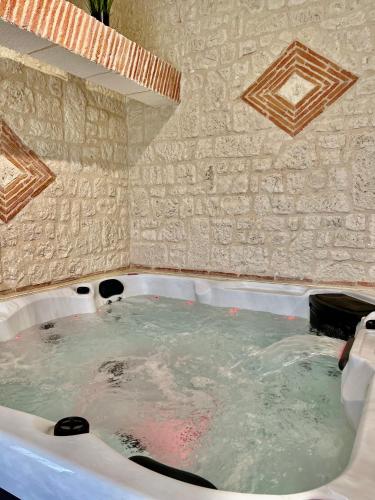 une baignoire remplie d'eau à côté d'un mur en pierre dans l'établissement Suite Privative Jacuzzi Sauna de la Villa Del Castagnol, à Saint-Nexans