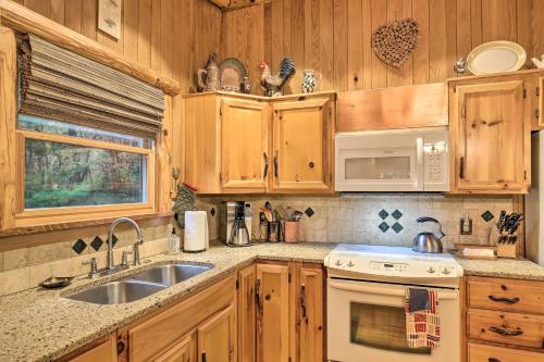 a kitchen with wooden cabinets and a sink and a stove at Fletcher Cabin Wraparound Deck and Pond Access in Fletcher
