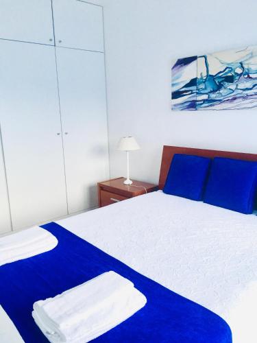a bedroom with a blue and white bed with blue pillows at Apartamento Vitória in Praia da Vitória
