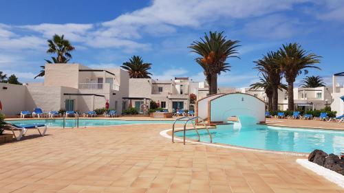 basen z palmami i budynkami w obiekcie CALIMA Lodge Corralejo w Corralejo