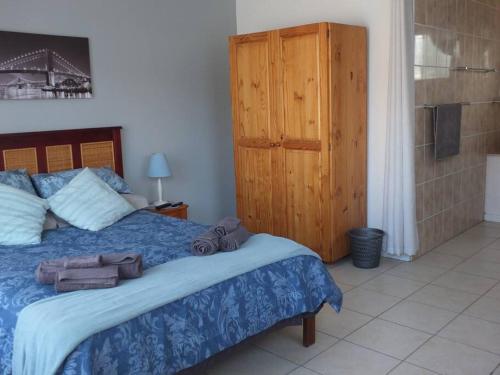 1 dormitorio con 1 cama y armario de madera en Heron Place sunny self-catering garden flatlet, en Port Alfred