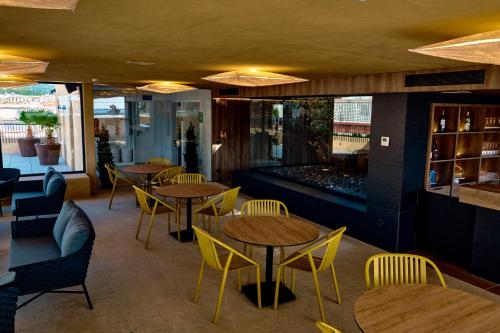 a restaurant with wooden tables and yellow chairs at Hotel Delfín in Tossa de Mar