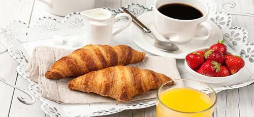 a table with croissants and a cup of coffee and strawberries at La Villa bed & breakfast in Milan