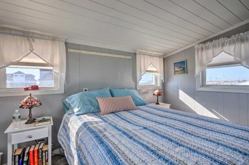a bedroom with a bed with a blue comforter and two windows at Seaside SK Getaway Steps to Matunuck Beach! in South Kingstown