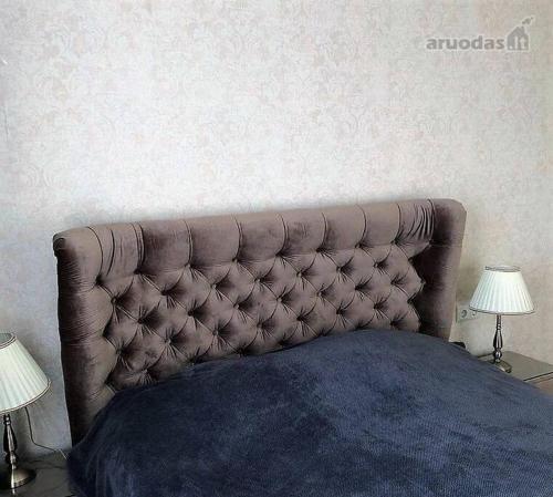 cabecero de cama en un dormitorio con 2 lámparas en BestToRest old town apartamant, en Klaipėda