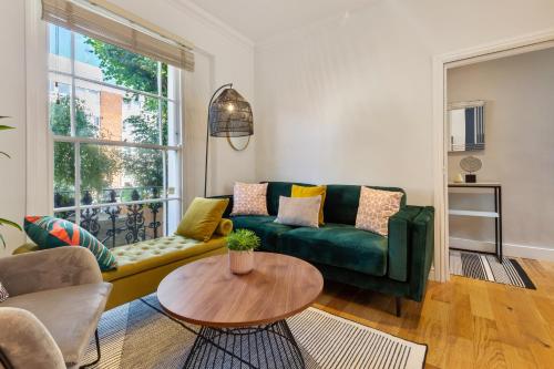 a living room with a green couch and a table at Camden Home - Barracks Properties in London