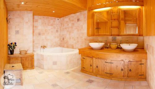 une salle de bain avec deux lavabos et une baignoire dans l'établissement 2AlpesChalets - Chalet Marie 2 - Standing et Sauna aux pieds des pistes, à Les Deux Alpes
