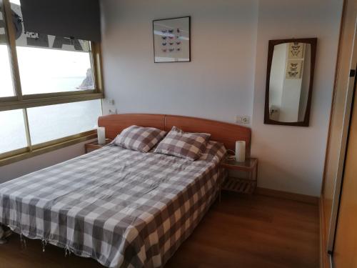 a bedroom with a bed with a checkered blanket at Principado Marina II in Benidorm