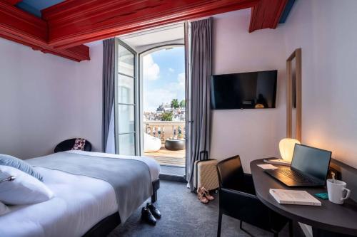 um quarto de hotel com uma cama e uma secretária com um computador portátil em Best Western Premier Hotel de la Cite Royale em Loches