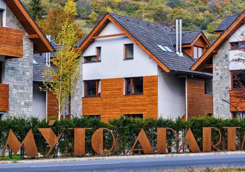 a house with a wooden sign in front of it at Mýto Apartments BERGMAX, Ski Jasná Chopok 10min transit - Resort Mýto Apartments, parking free in Mýto pod Ďumbierom