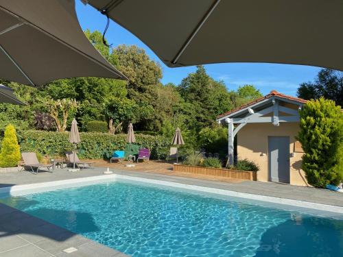 a swimming pool in a yard with an umbrella at Le Petit Manoir de Vitrac in Vitrac