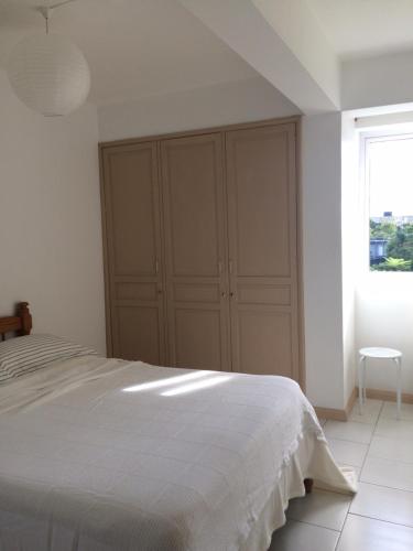 a white bedroom with a bed and a window at La Péninsule Town Apartment Curepipe No 4 in Curepipe