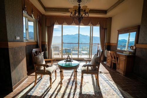 a living room with a table and chairs and a large window at Qingjing Baiyun Resort in Renai