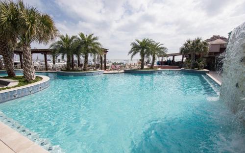 a large swimming pool with palm trees in a resort at Gaido's Seaside Inn in Galveston