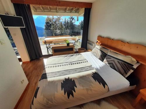 a bedroom with a bed and a large window at Chaleureux appartement aux pieds des pistes in Chamrousse