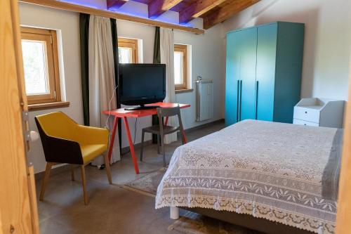 a bedroom with a bed and a desk with a television at IL Sogno in Montesano sulla Marcellana