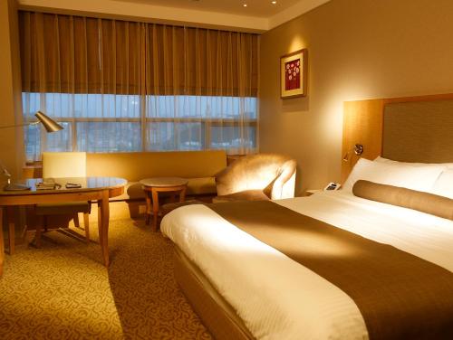 a hotel room with a bed and a couch and a table at Daegu Grand Hotel in Daegu