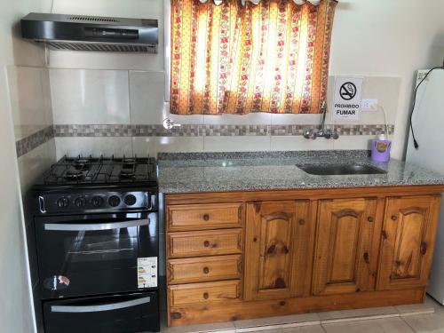 a kitchen with a stove and a sink at Navarro Departamentos Temporarios in Navarro