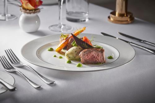 a white plate with meat and vegetables on a table at Bathen House Boutique Hotel in Bath