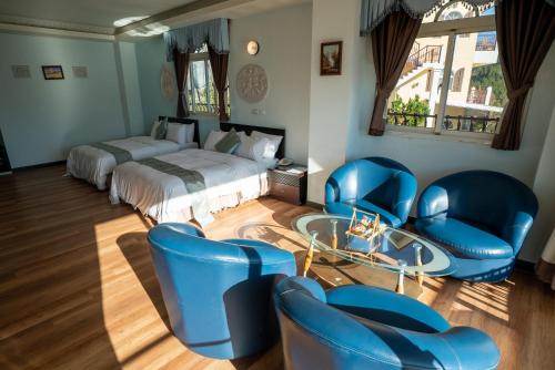 a bedroom with blue chairs and a bed and a table at Qingjing Baiyun Resort in Renai