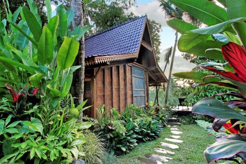 a small wooden house in the middle of a garden at Masakali Retreat in Ubud