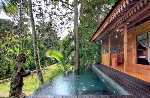 a swimming pool outside of a house in the woods at Masakali Retreat in Ubud