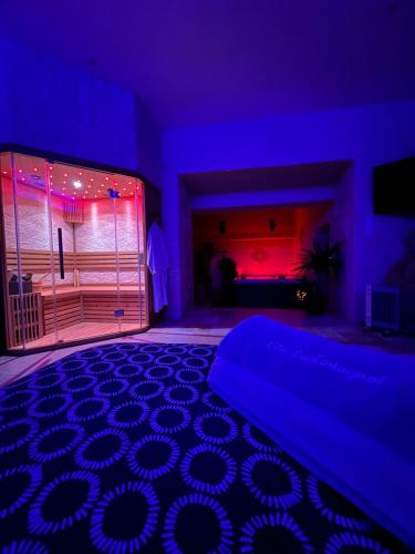 a bedroom with a bed and a room with purple lights at Suite Privative Jacuzzi Sauna de la Villa Del Castagnol in Saint-Nexans