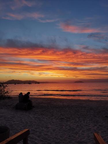 a couple sitting on the beach watching the sunset at Apart da Cachoeira in Florianópolis