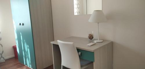 a desk with a lamp and a white chair at Le Lune di Diana in Matera