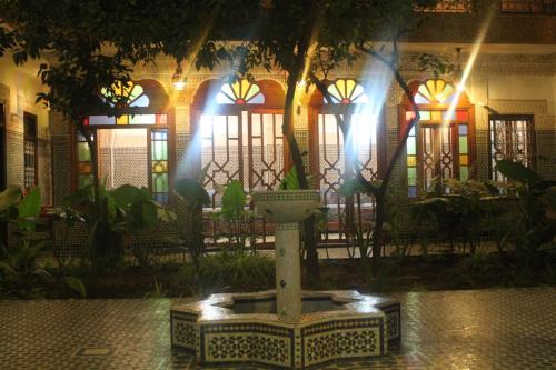 a fountain in front of a building with lights at Riad Les Chrifis Navette Aéroport 24 sur 24 in Fès