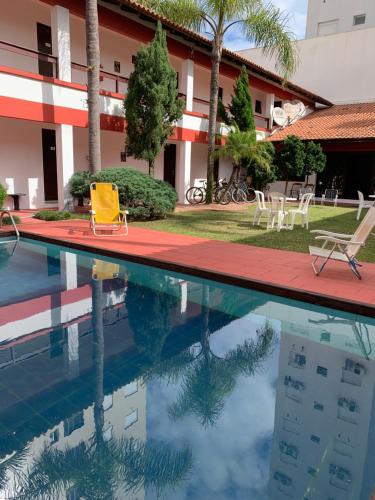 a pool in front of a hotel with chairs and a building at Hotel Praia Bonita in Capão da Canoa