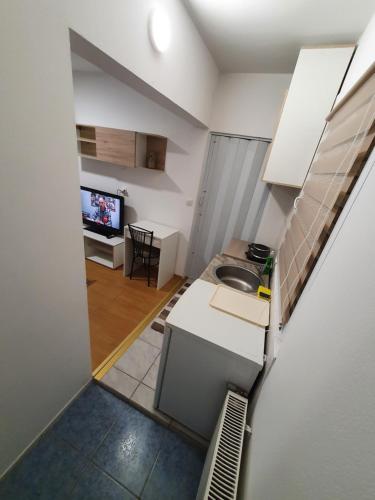 a small kitchen with a sink and a tv at Garsonjera u centru Prnjavor in Prnjavor