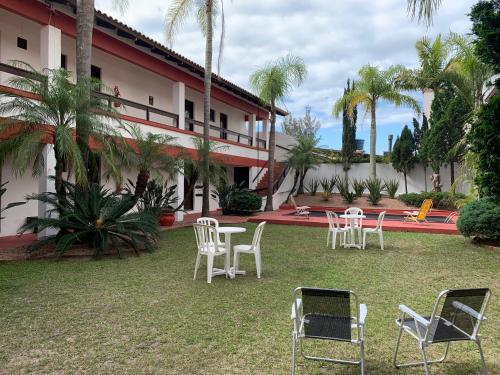 a group of chairs and tables in front of a building at Hotel Praia Bonita in Capão da Canoa