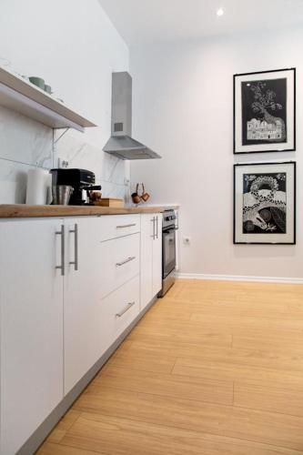 a kitchen with white cabinets and a wooden floor at Ohrid Center Galerie House in Ohrid