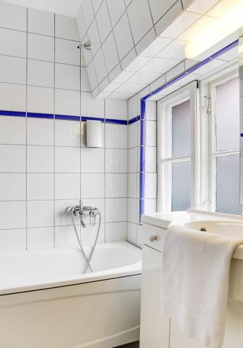 a white bathroom with a tub and a sink at Anno 1793 Sekelgården in Ystad