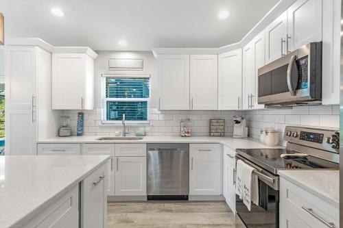 a white kitchen with white cabinets and stainless steel appliances at BRAND NEW Rental with Luxury Pool - Villa Rosalie - Roelens Vacations in Englewood