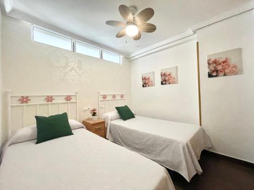 een kamer met 2 bedden en een plafondventilator bij Lovely holidays in Benidorm