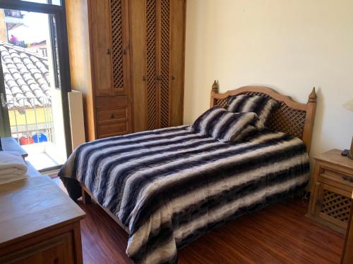a bedroom with a bed with a striped blanket at Casa Galindo *a unos pasos del centro* in Zacatlán